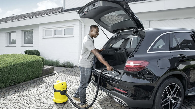 ragazzo che pulisce bagagliaio con aspiratore liquidi e solidi