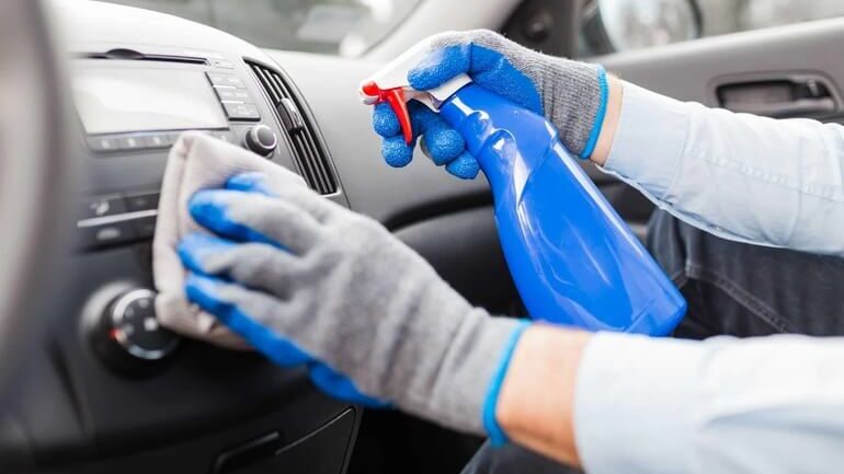 persona con guanti che esegue igienizzazione auto