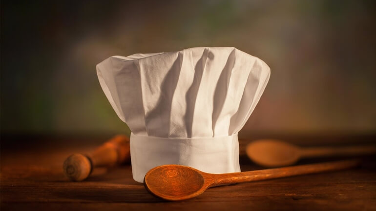 cappello da cuoco chef su tagliere con cucchiai dilegno
