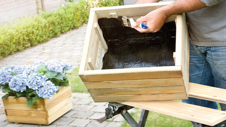 uomo che impermeabilizza scatola legno con gomma liquida